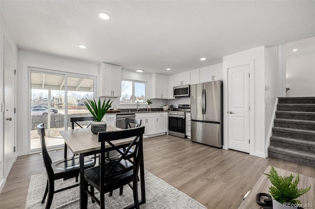 dining room featuring light wood-type flooring, stairway, a textured ceiling, and recessed lighting