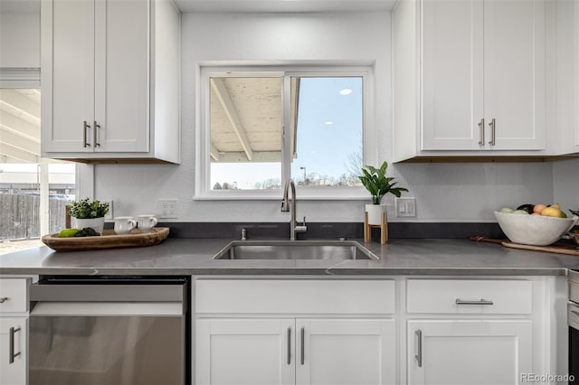 kitchen with a textured wall, a sink, white cabinetry, dishwasher, and dark countertops