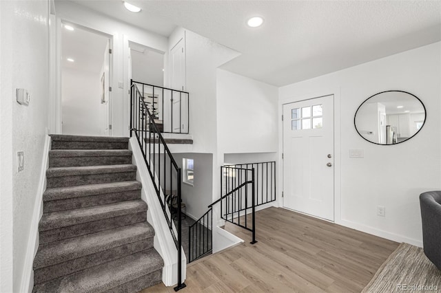 foyer featuring recessed lighting, light wood-style flooring, baseboards, and stairs