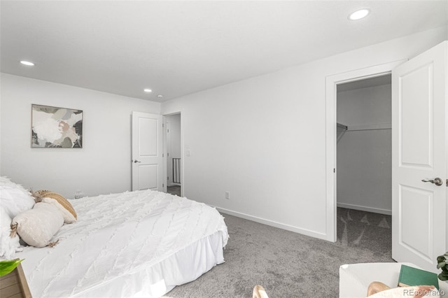 bedroom featuring a walk in closet, carpet flooring, baseboards, and recessed lighting