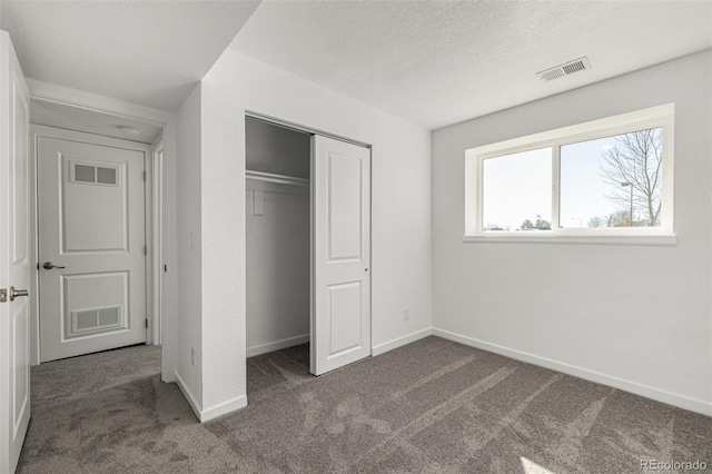 unfurnished bedroom featuring a textured ceiling, carpet flooring, and visible vents