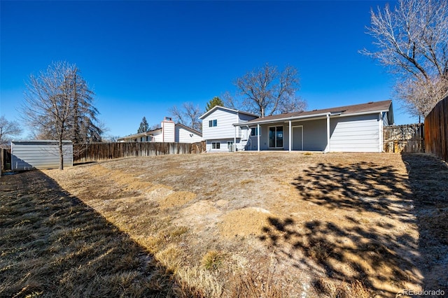 rear view of property with fence and an outdoor structure