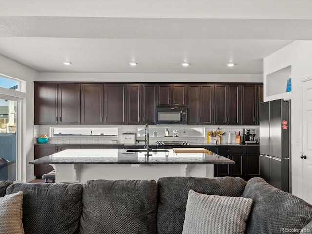 21901 E 42nd Pl, Aurora, CO 80019 - kitchen featuring stainless steel refrigerator, black microwave, a sink, stone countertops, and open floor plan
