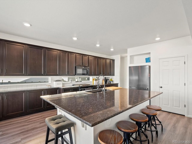 21901 E 42nd Pl, Aurora, CO 80019 - kitchen featuring appliances with stainless steel finishes, a sink, light wood finished floors, a kitchen bar, and recessed lighting