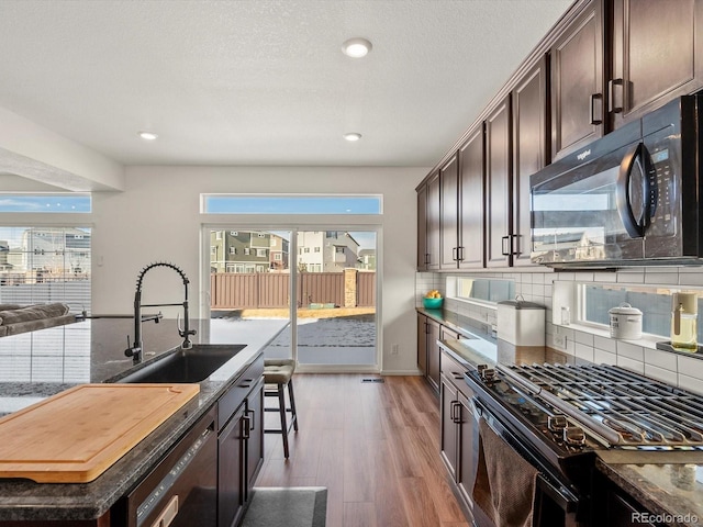 21901 E 42nd Pl, Aurora, CO 80019 - kitchen with black appliances, a sink, dark brown cabinetry, light wood-style flooring, and decorative backsplash