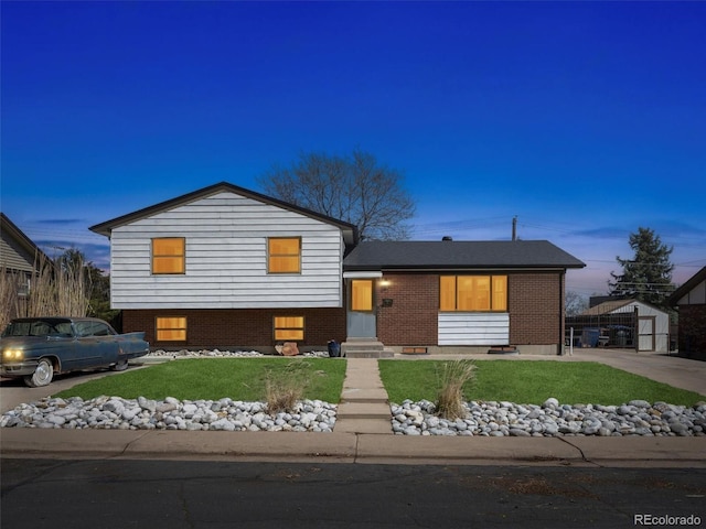 tri-level home featuring entry steps, a front lawn, brick siding, and an outbuilding