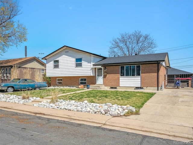 split level home with fence, driveway, a front lawn, and brick siding