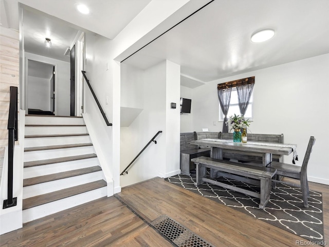 dining area featuring wood finished floors, baseboards, and stairway