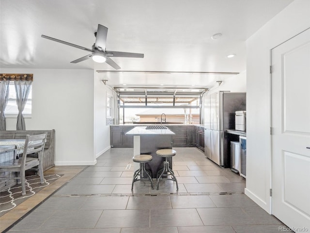 kitchen featuring a center island, baseboards, a wealth of natural light, and ceiling fan