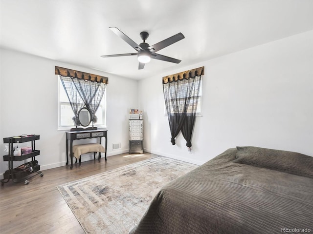 bedroom with visible vents, baseboards, a ceiling fan, and wood finished floors