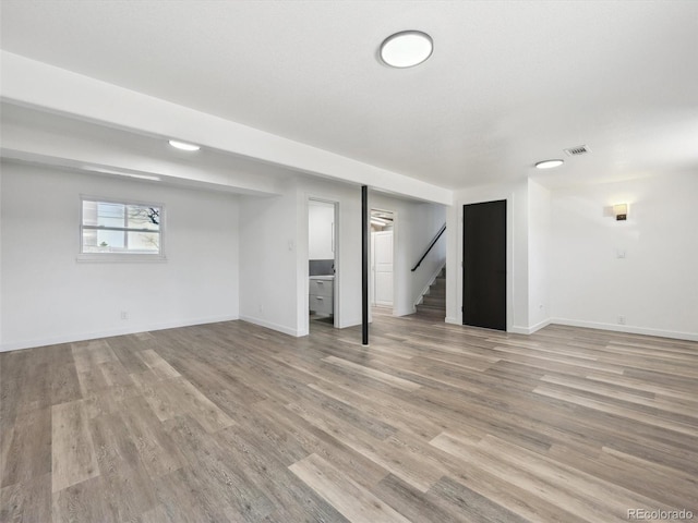 basement featuring baseboards, wood finished floors, visible vents, and stairs