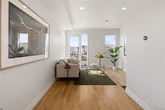 corridor featuring baseboards, light wood finished floors, and recessed lighting