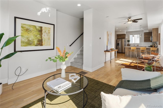 living area with light wood-style floors, stairway, ceiling fan, baseboards, and recessed lighting