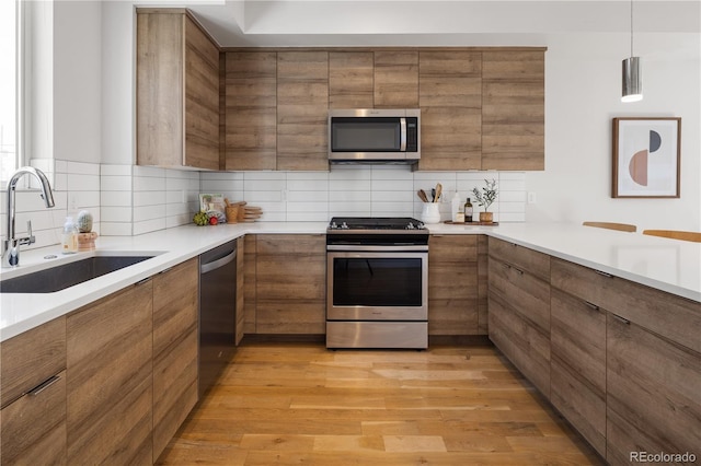 kitchen with appliances with stainless steel finishes, a sink, brown cabinets, and decorative backsplash