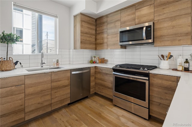 kitchen with appliances with stainless steel finishes, a sink, brown cabinets, and backsplash