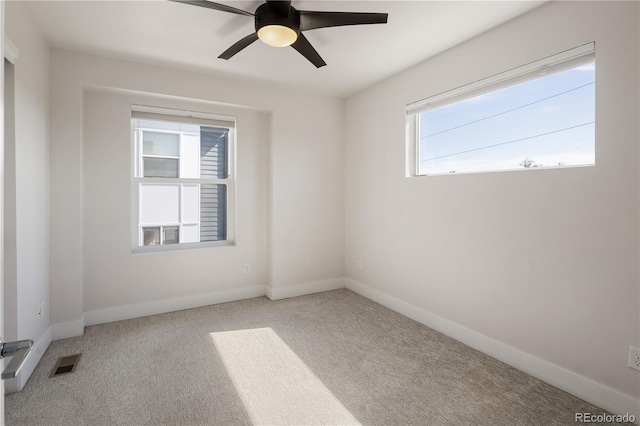 carpeted spare room featuring a ceiling fan and baseboards