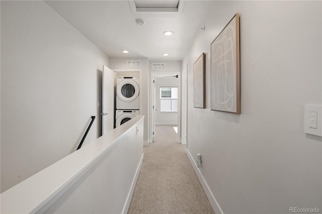 hallway with estacked washer and dryer, light colored carpet, baseboards, and recessed lighting