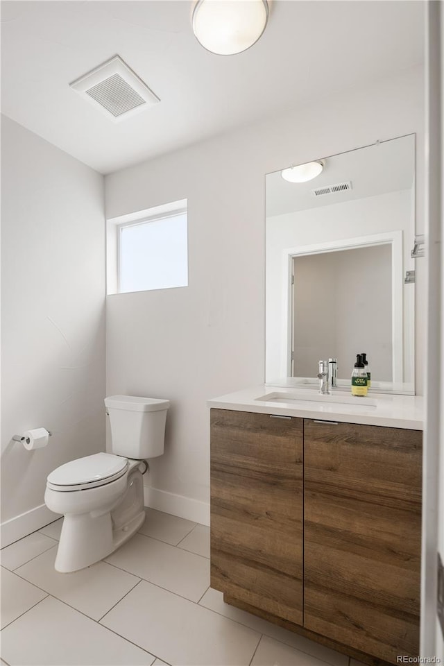 half bath featuring toilet, vanity, baseboards, and tile patterned flooring