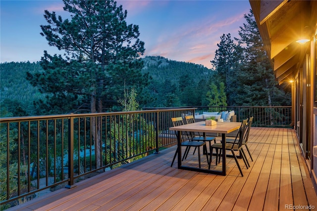 1298 Meadow View Dr, Evergreen, CO 80439 - deck at dusk with a forest view, outdoor dining area, and a mountain view
