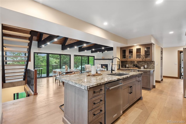 1298 Meadow View Dr, Evergreen, CO 80439 - kitchen featuring dishwasher, a fireplace, decorative backsplash, a kitchen island with sink, and light stone countertops