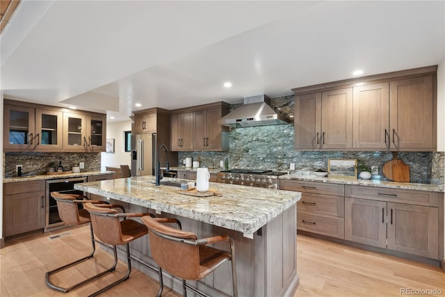 1298 Meadow View Dr, Evergreen, CO 80439 - kitchen with wall chimney exhaust hood, backsplash, light wood finished floors, recessed lighting, and a breakfast bar area