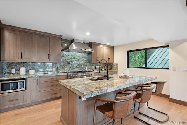 1298 Meadow View Dr, Evergreen, CO 80439 - kitchen featuring stainless steel appliances, wall chimney exhaust hood, light wood-type flooring, tasteful backsplash, and recessed lighting