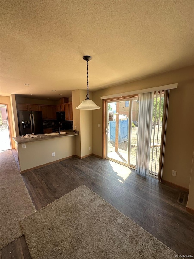 kitchen featuring a healthy amount of sunlight, dark hardwood / wood-style flooring, sink, and black fridge with ice dispenser