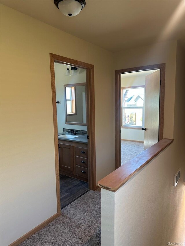 corridor featuring sink and dark colored carpet