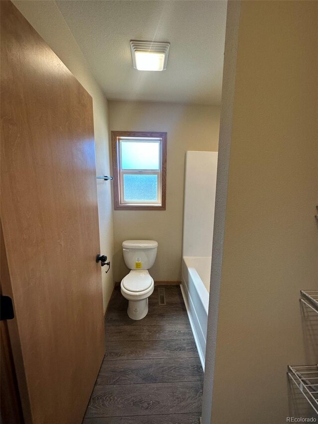 bathroom featuring hardwood / wood-style flooring, shower / bath combination, and toilet