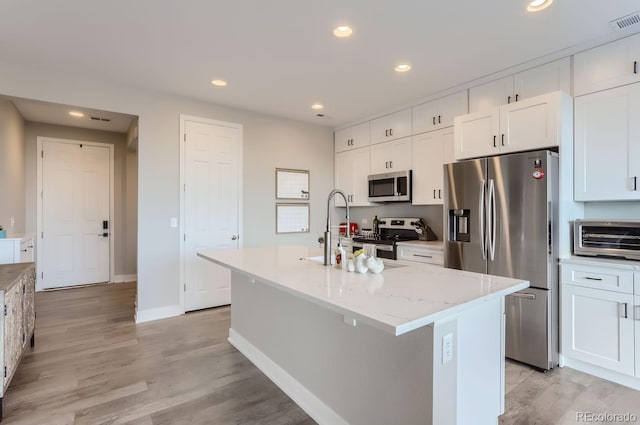 6645 Dry Fork Dr, Frederick, CO 80516 - kitchen with stainless steel appliances, white cabinets, an island with sink, recessed lighting, and light stone counters