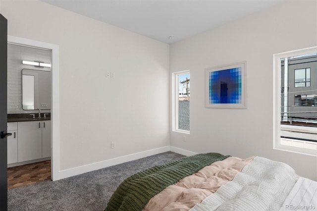 carpeted bedroom featuring a sink, multiple windows, and baseboards