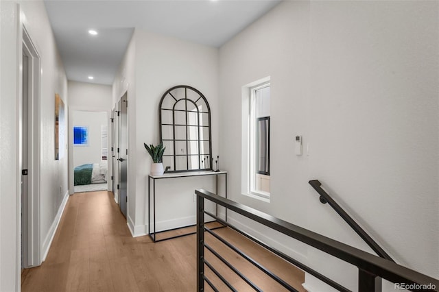 hall featuring light wood finished floors, recessed lighting, an upstairs landing, and baseboards