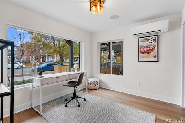 office space with a wall unit AC, wood finished floors, and baseboards