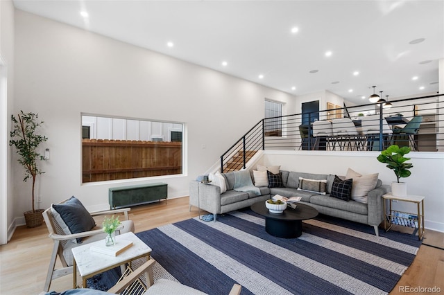 living area featuring a towering ceiling, light wood-type flooring, and recessed lighting