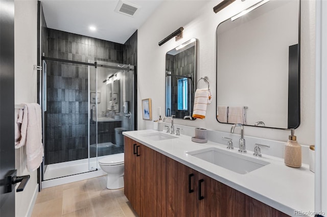 bathroom featuring toilet, a shower stall, and double vanity