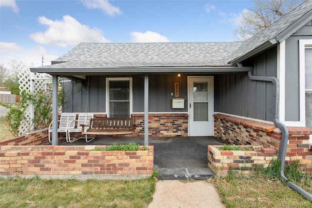 property entrance featuring board and batten siding, a shingled roof, and covered porch