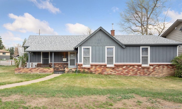 view of front of property with a shingled roof, board and batten siding, a front yard, a chimney, and covered porch