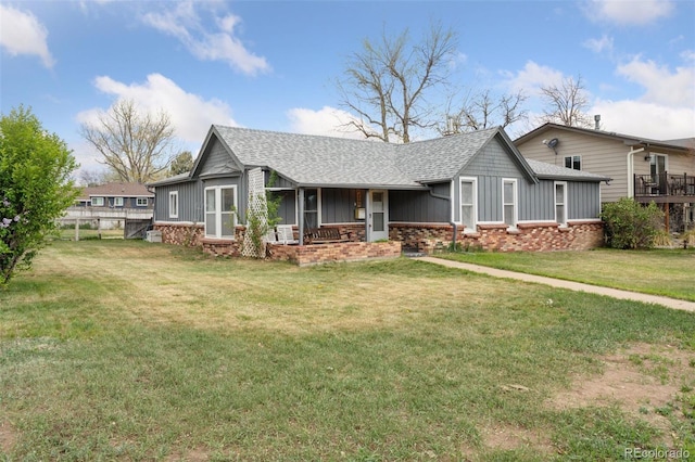 ranch-style house featuring a porch, a shingled roof, board and batten siding, and a front yard