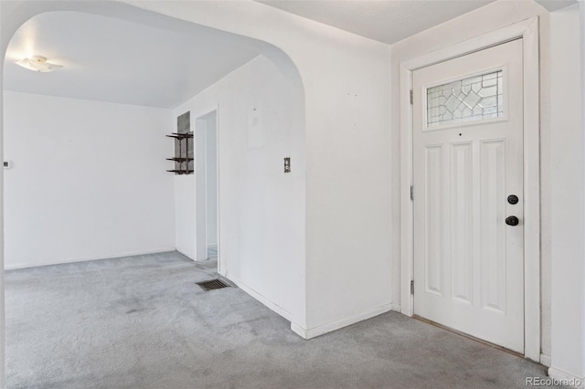 carpeted foyer entrance featuring arched walkways