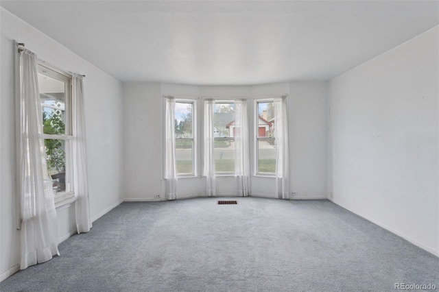 empty room with baseboards, visible vents, and carpet