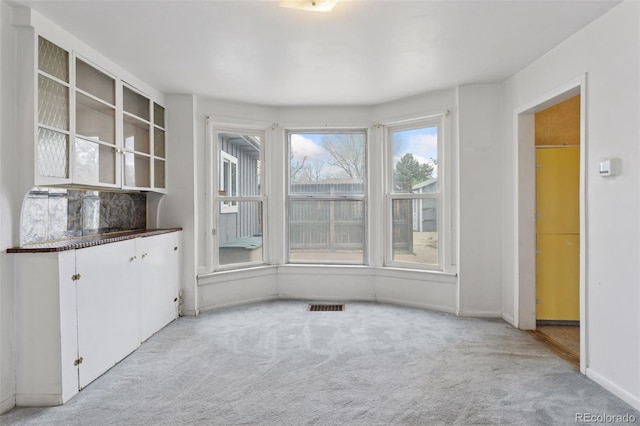 unfurnished dining area with visible vents, carpet flooring, and baseboards