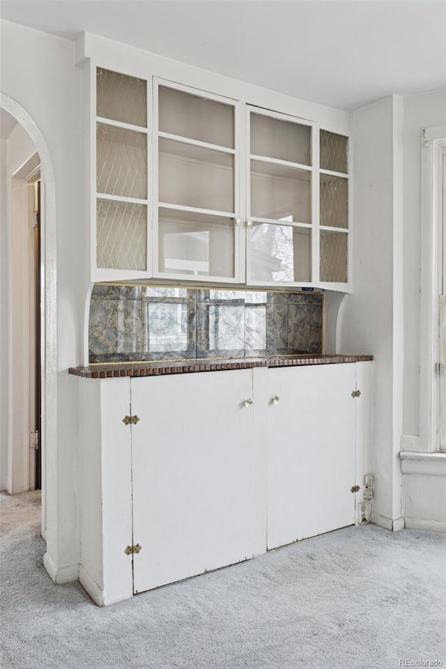kitchen featuring carpet flooring, arched walkways, and dark countertops