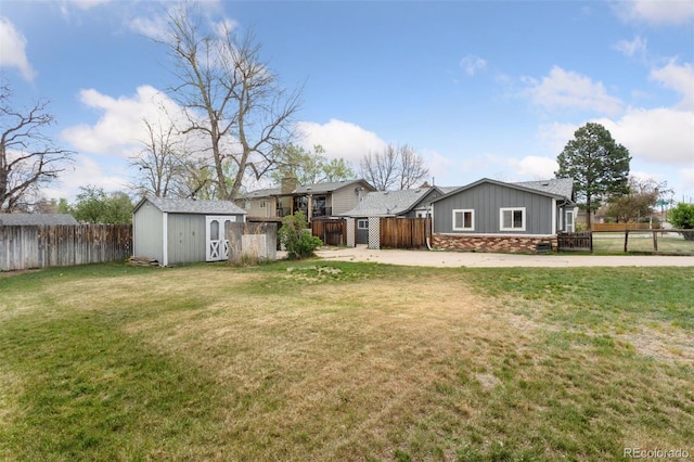 view of yard with a storage shed, an outbuilding, a fenced backyard, and driveway