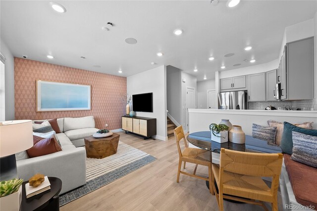 17137 W 91st Ln, Arvada, CO 80007 - living room featuring wallpapered walls, an accent wall, light wood-style flooring, baseboards, and recessed lighting