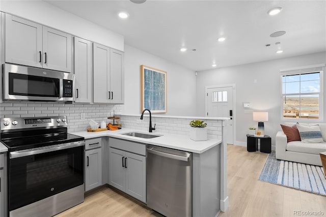 17137 W 91st Ln, Arvada, CO 80007 - kitchen with stainless steel appliances, a sink, gray cabinets, backsplash, and light wood finished floors