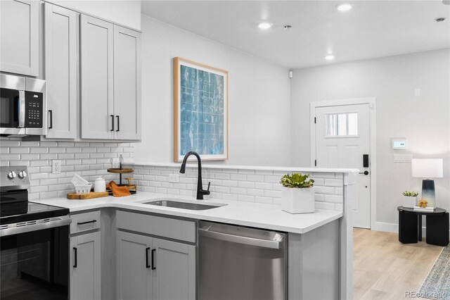 17137 W 91st Ln, Arvada, CO 80007 - kitchen with stainless steel appliances, a sink, decorative backsplash, light countertops, and gray cabinets