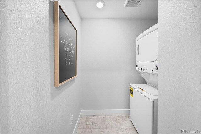 17137 W 91st Ln, Arvada, CO 80007 - clothes washing area featuring stacked washer and clothes dryer, baseboards, and light marble finish floors