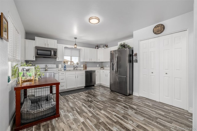 kitchen featuring appliances with stainless steel finishes, sink, dark hardwood / wood-style flooring, and white cabinetry