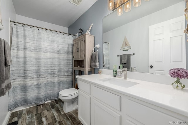 bathroom featuring toilet, vanity, wood-type flooring, and walk in shower