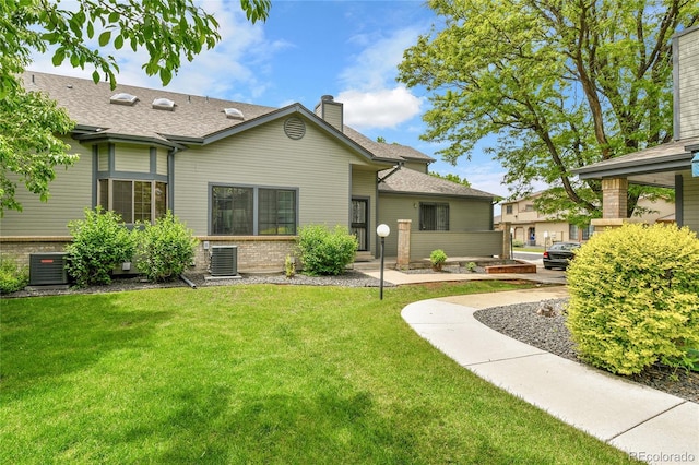 9183 W Cedar Dr Unit 2, Lakewood, CO 80226 - back of house with a chimney, a lawn, central air condition unit, and brick siding